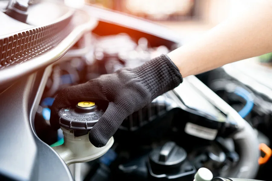 Một kỹ thuật viên đang mở nắp bình chứa dầu phanh trong xe