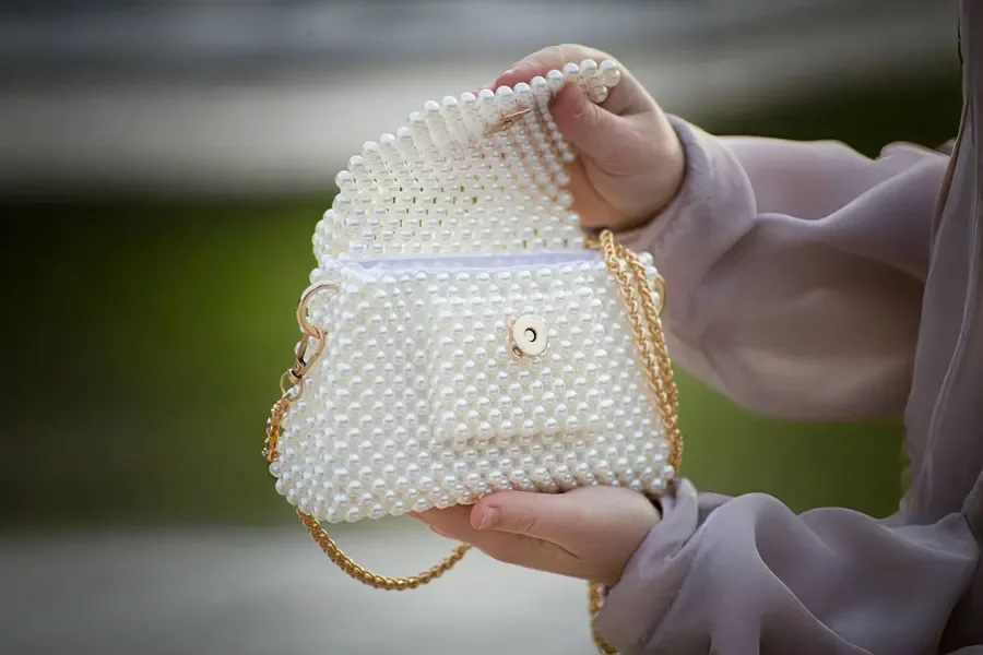 A woman holding a pearl-beaded bag