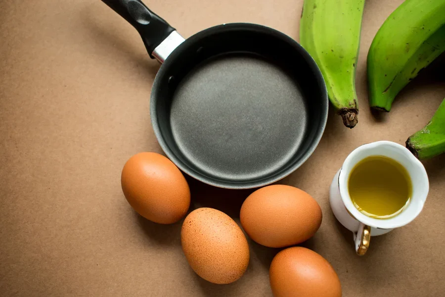 Chảo Teflon màu đen không nắp trên bàn với trứng