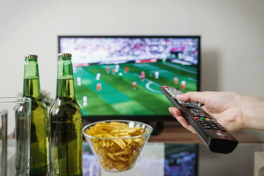 Điều khiển từ xa chỉ vào TV với hình ảnh thể thao trên màn hình