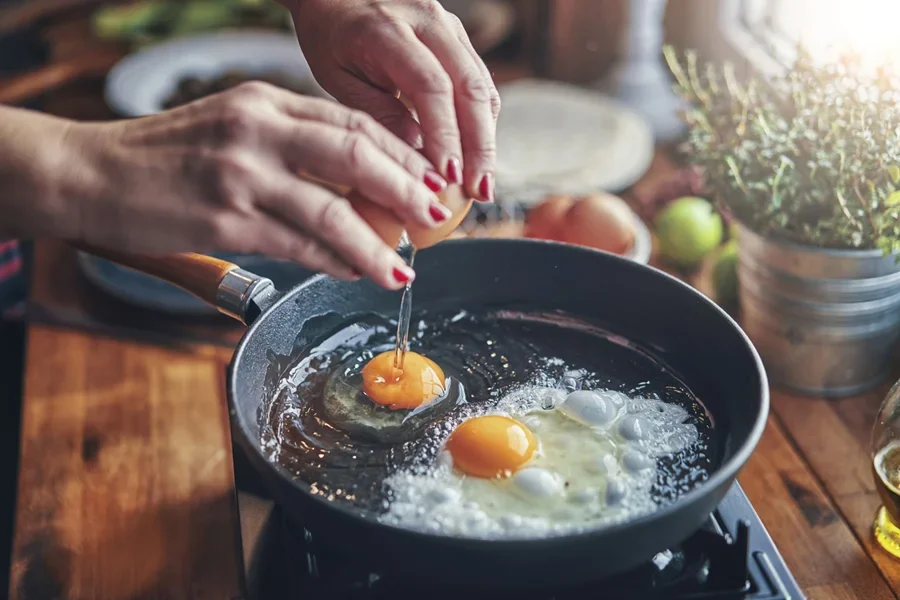 Hai quả trứng đang được chiên trên chảo với lửa lớn