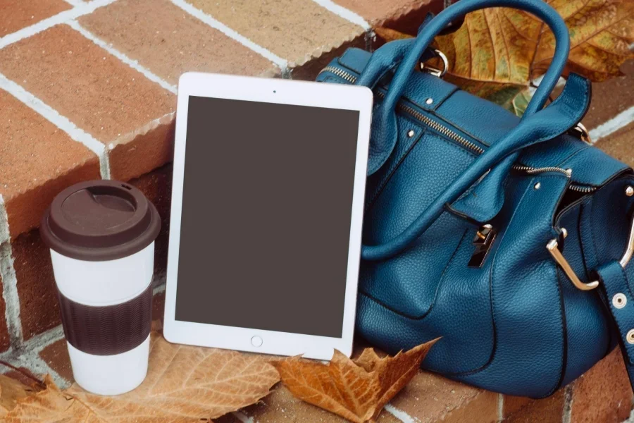 Ipad trắng bên cạnh túi xách da xanh 2 chiều