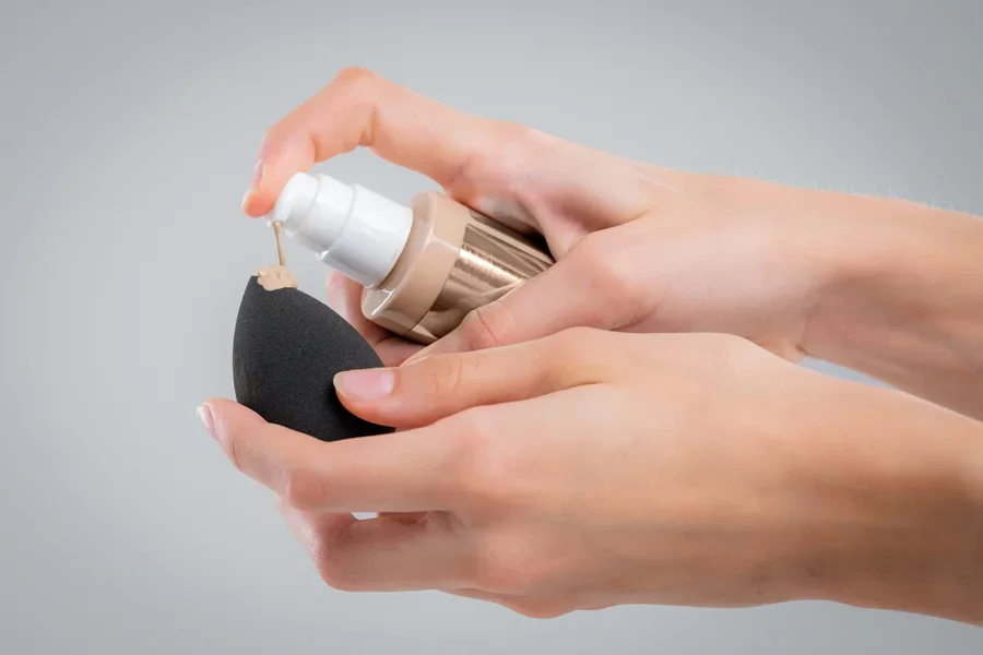 Phụ nữ thoa skin tint lên miếng bọt biển trang điểm