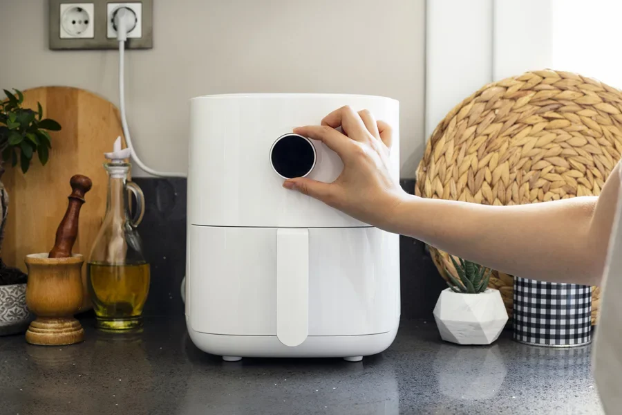 Phụ nữ đang điều chỉnh nhiệt độ của nồi chiên không dầu hiện đại