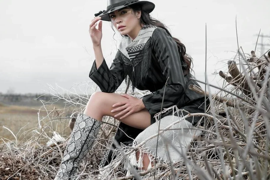 Người phụ nữ mặc trang phục cowgirl ngồi trên đống cỏ